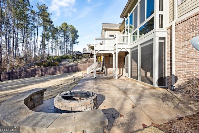 view of patio featuring a sunroom, a fire pit, and a deck