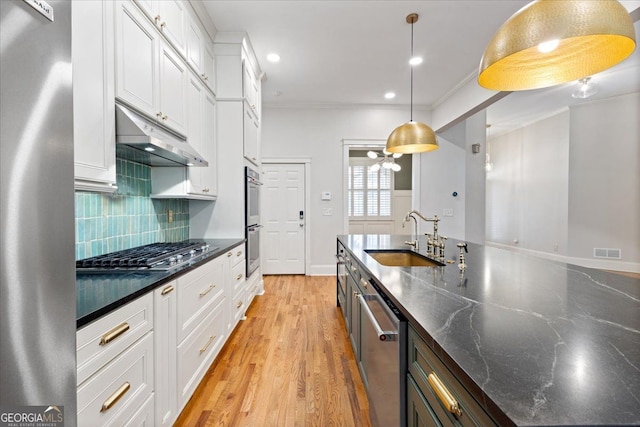 kitchen featuring stainless steel appliances, decorative backsplash, white cabinets, and pendant lighting