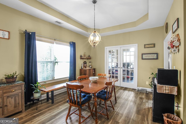 dining room with a raised ceiling, french doors, dark hardwood / wood-style floors, and a notable chandelier