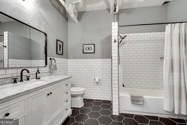 full bathroom featuring tile patterned flooring, toilet, shower / tub combo with curtain, vanity, and tile walls