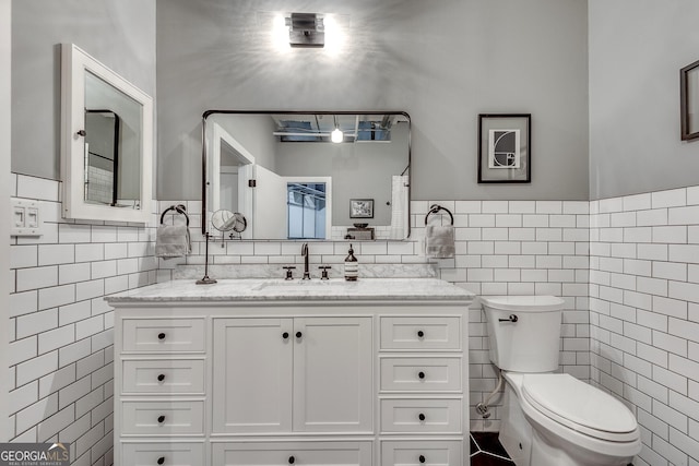 bathroom featuring vanity, toilet, and tile walls