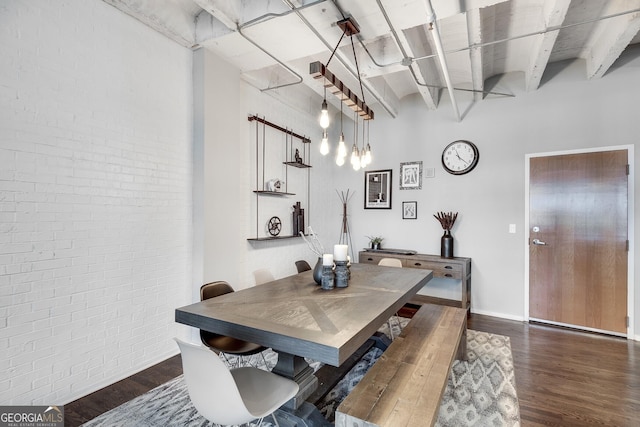 dining space with dark hardwood / wood-style flooring and brick wall