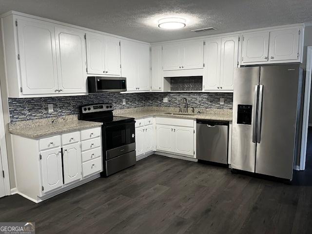 kitchen with sink, dark hardwood / wood-style floors, a textured ceiling, white cabinets, and appliances with stainless steel finishes