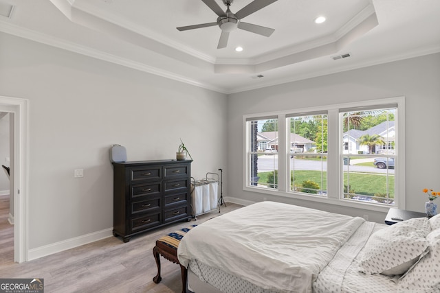 bedroom featuring a tray ceiling, ceiling fan, ornamental molding, and light hardwood / wood-style floors