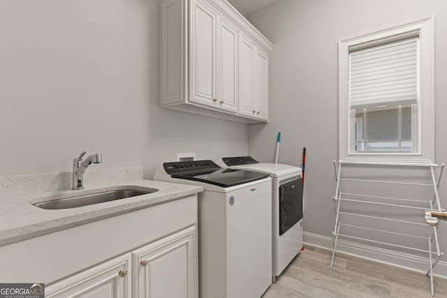 clothes washing area with cabinets, independent washer and dryer, sink, and light wood-type flooring