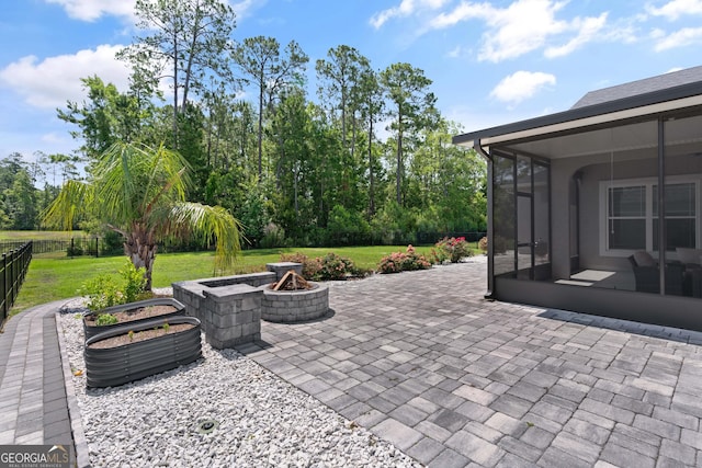 view of patio featuring an outdoor fire pit and a sunroom