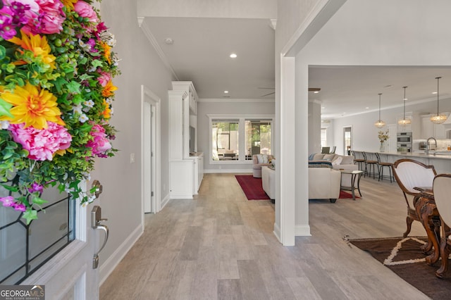 entrance foyer with light wood-type flooring, ceiling fan, ornamental molding, and sink