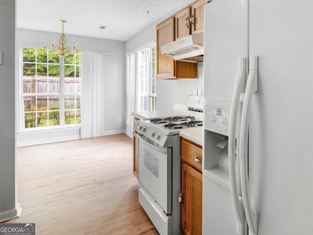 kitchen featuring pendant lighting, white appliances, light hardwood / wood-style flooring, and a chandelier