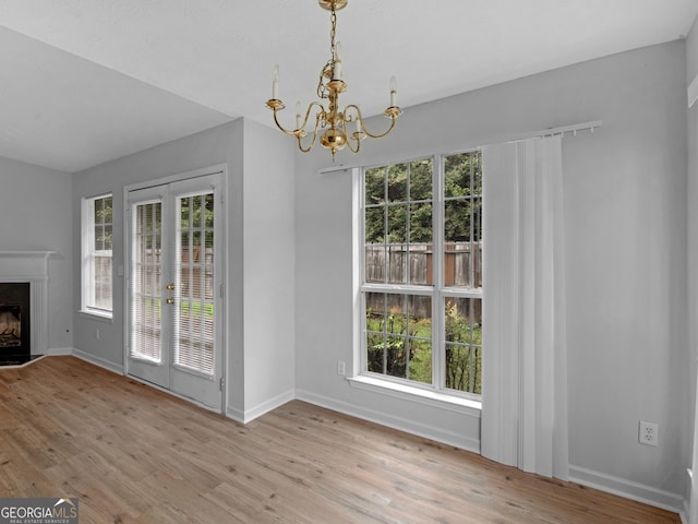 unfurnished dining area featuring light wood-type flooring and an inviting chandelier