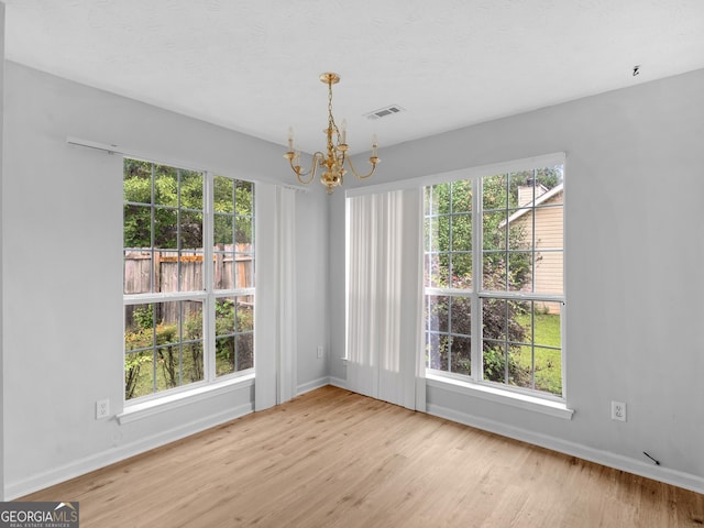 unfurnished dining area with light hardwood / wood-style floors and an inviting chandelier