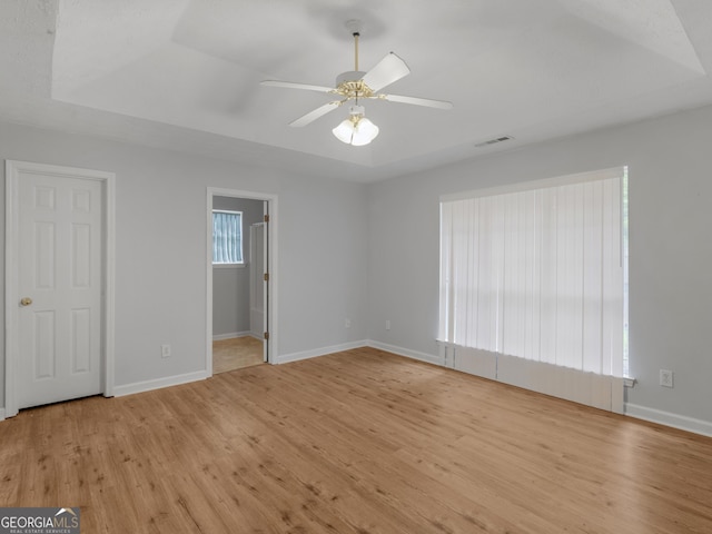 interior space with ceiling fan, a raised ceiling, and light hardwood / wood-style flooring