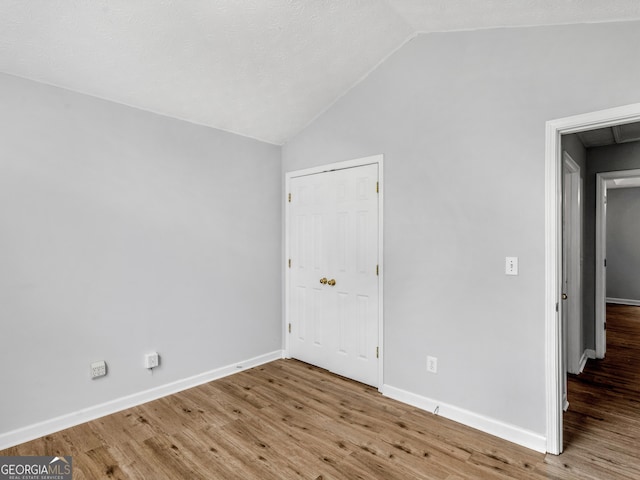 empty room with hardwood / wood-style floors and lofted ceiling