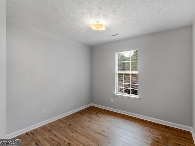 spare room with hardwood / wood-style floors and a textured ceiling