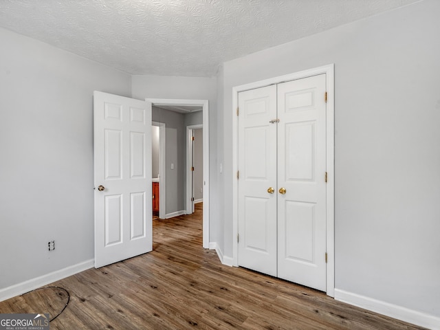 unfurnished bedroom featuring hardwood / wood-style flooring, a textured ceiling, and a closet