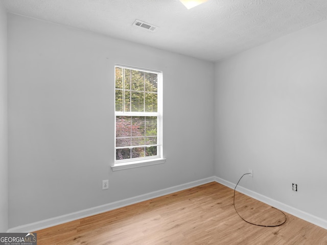 unfurnished room with a textured ceiling, light hardwood / wood-style floors, and a healthy amount of sunlight