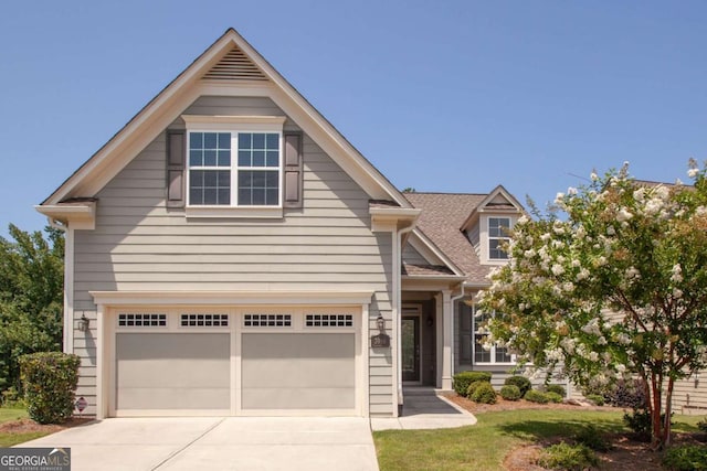 view of front of home featuring a front yard, an attached garage, driveway, and a shingled roof