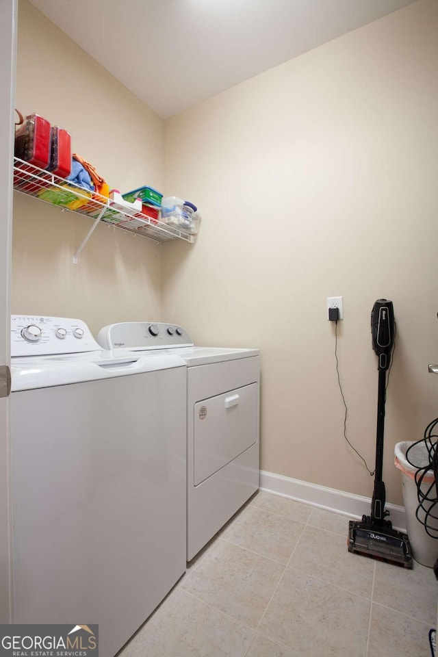 washroom featuring light tile patterned flooring, laundry area, baseboards, and separate washer and dryer