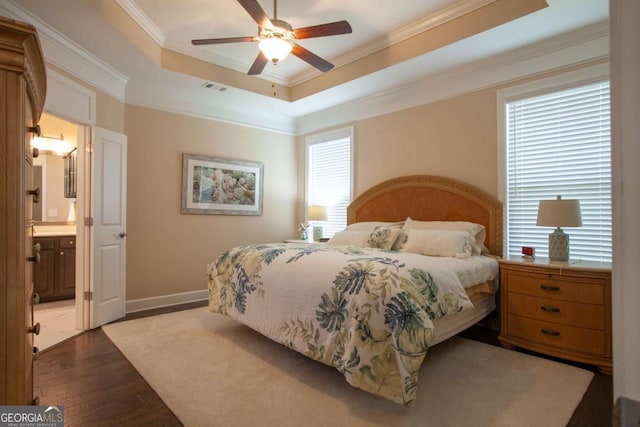 bedroom featuring ceiling fan, a raised ceiling, crown molding, hardwood / wood-style floors, and ensuite bathroom