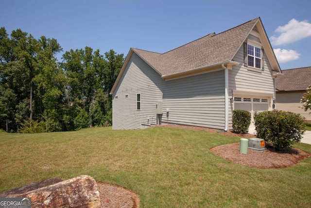 view of home's exterior with an attached garage, a yard, and roof with shingles