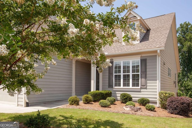 view of front of house featuring a front lawn, a shingled roof, a garage, and concrete driveway