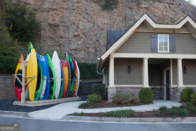 view of front of home with stone siding, a porch, and playground community