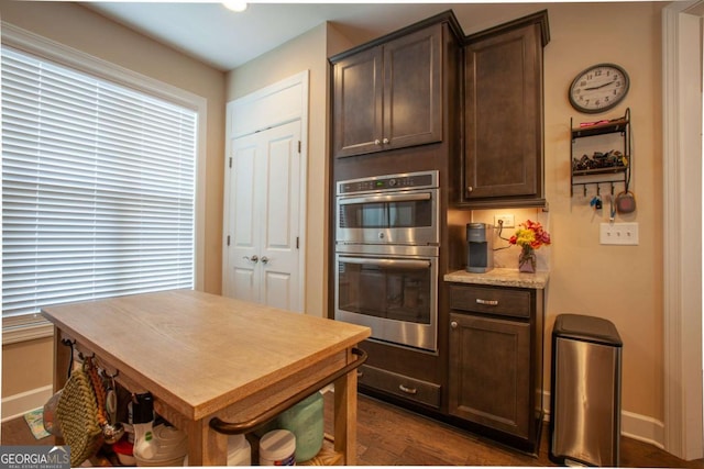 kitchen featuring dark brown cabinets, dark hardwood / wood-style flooring, and double oven