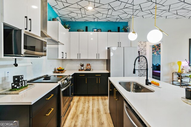 kitchen featuring white cabinets, stainless steel appliances, hanging light fixtures, and sink