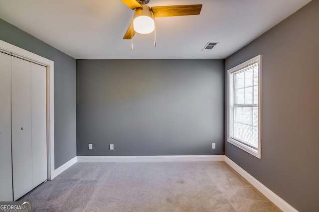 unfurnished bedroom with ceiling fan, light carpet, and a closet