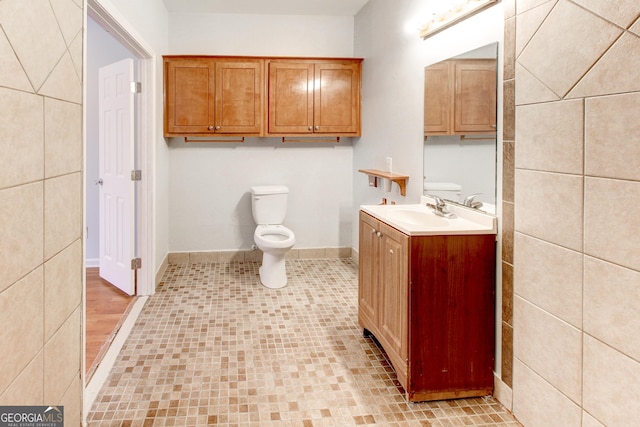 bathroom with tile patterned flooring, vanity, toilet, and tile walls