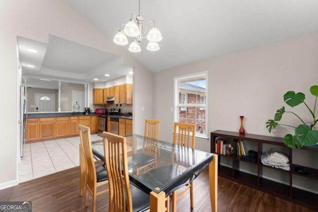 dining area featuring light hardwood / wood-style flooring, lofted ceiling, and an inviting chandelier