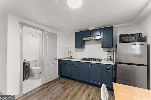 kitchen with blue cabinetry, sink, stainless steel appliances, and tasteful backsplash