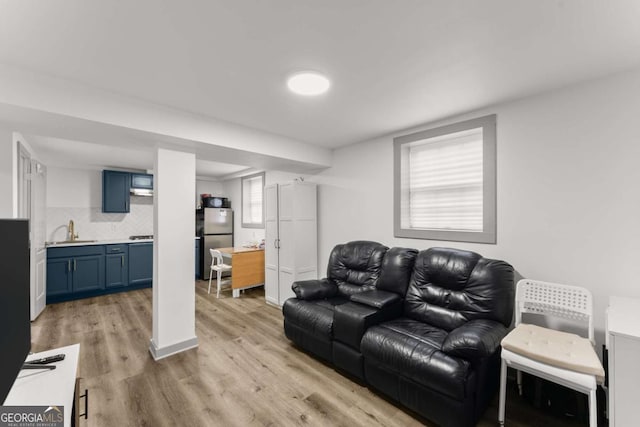 living room with plenty of natural light, sink, and light hardwood / wood-style flooring