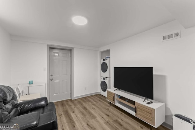 living room with light wood-type flooring and stacked washing maching and dryer