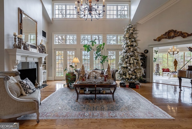 living room with a notable chandelier, wood-type flooring, a high ceiling, and french doors