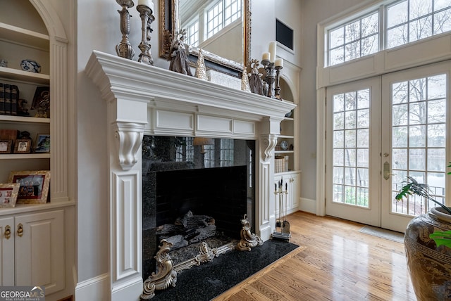 living room with a premium fireplace, built in features, and a healthy amount of sunlight