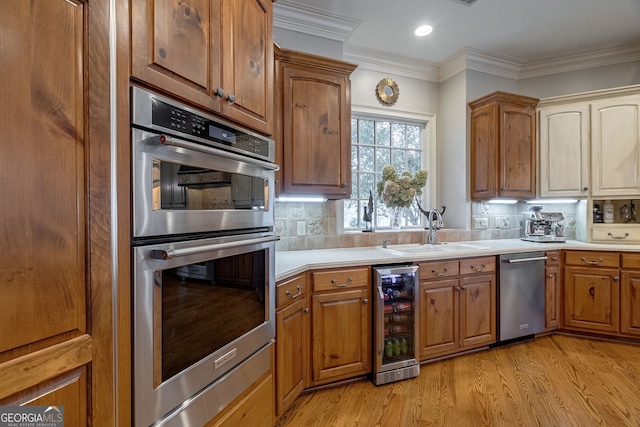 kitchen featuring light wood-type flooring, tasteful backsplash, stainless steel appliances, beverage cooler, and sink