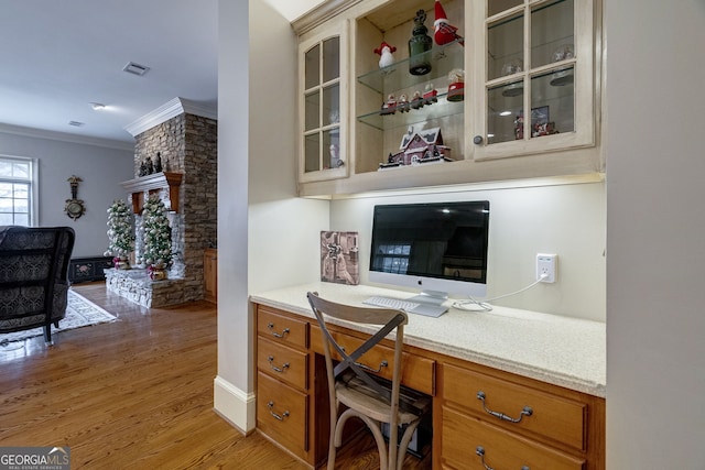 office with built in desk, hardwood / wood-style flooring, and ornamental molding