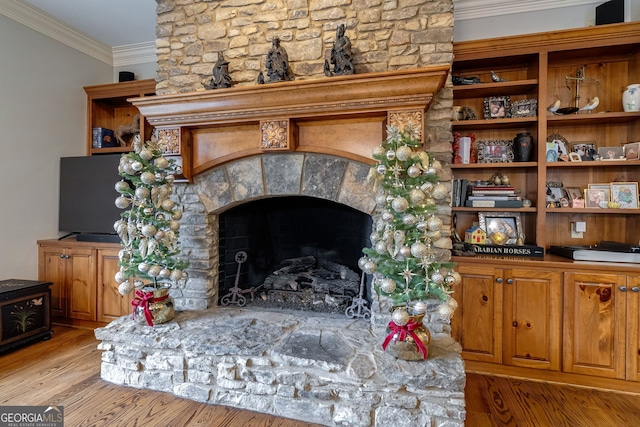 living room featuring light hardwood / wood-style flooring, a stone fireplace, and ornamental molding