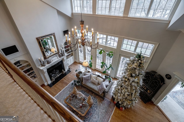 living room with a premium fireplace, plenty of natural light, a high ceiling, and an inviting chandelier