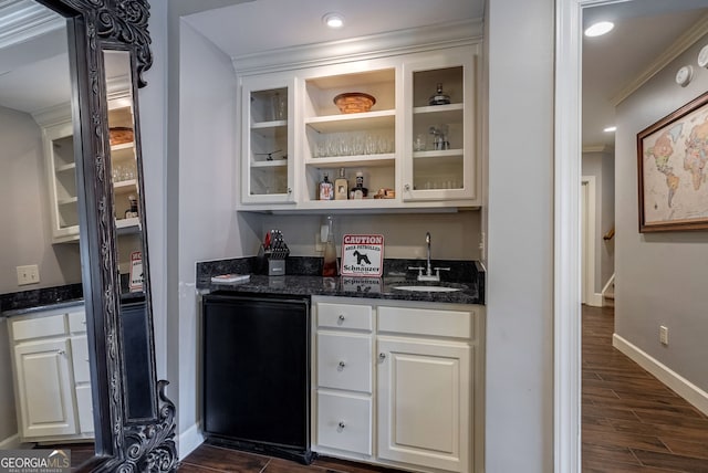 bar with refrigerator, sink, dark stone countertops, ornamental molding, and white cabinetry