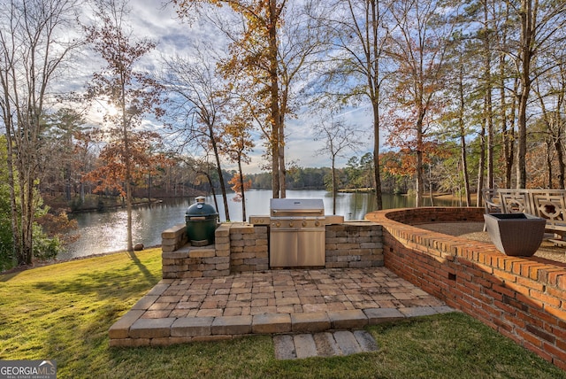 view of patio featuring grilling area, a water view, and an outdoor kitchen