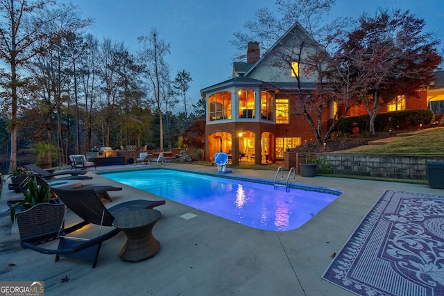 pool at dusk featuring a jacuzzi and a patio