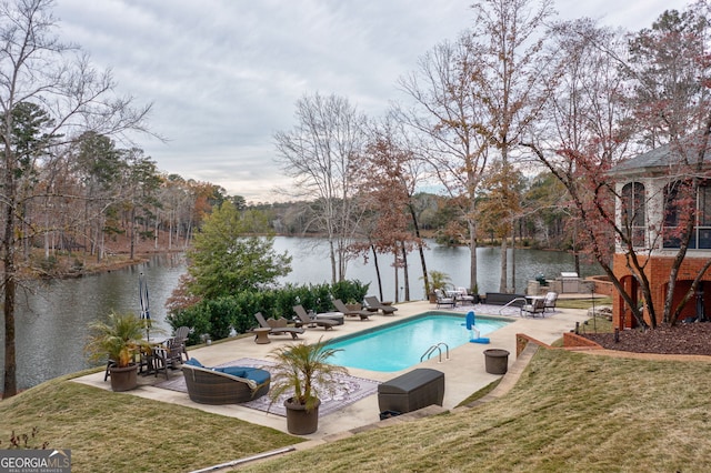 view of pool featuring a lawn, a patio area, and a water view