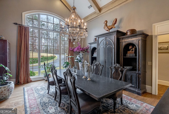 dining space featuring beam ceiling, high vaulted ceiling, light hardwood / wood-style floors, and a notable chandelier