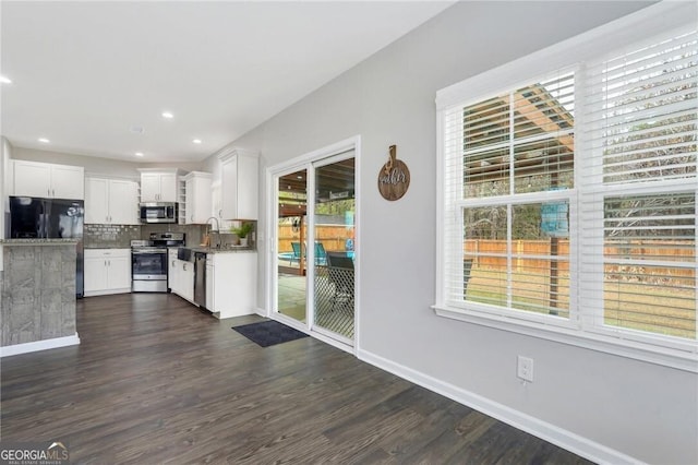 kitchen with white cabinets, decorative backsplash, stainless steel appliances, and a wealth of natural light