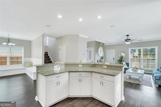 kitchen with white cabinets, ceiling fan with notable chandelier, decorative light fixtures, and a large island