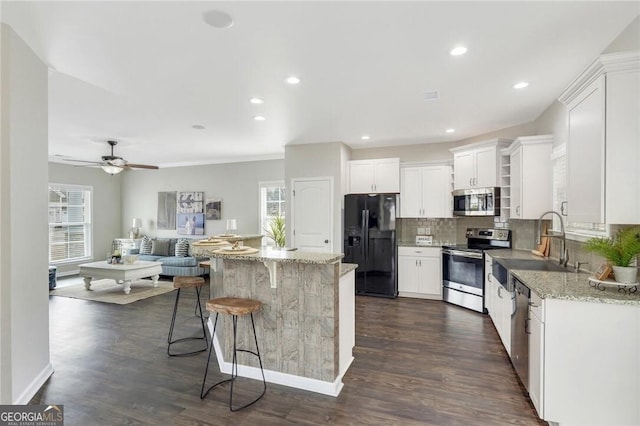 kitchen featuring white cabinets, a kitchen island, light stone countertops, and stainless steel appliances