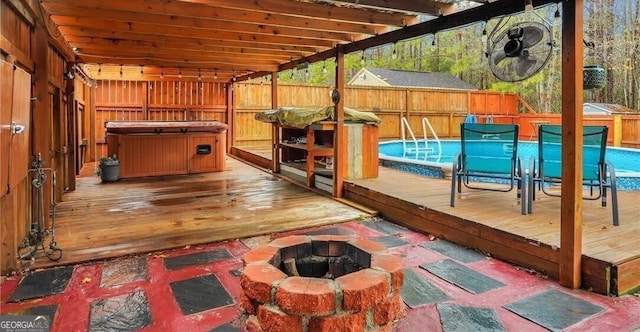 wooden terrace featuring a fire pit and a pool with hot tub