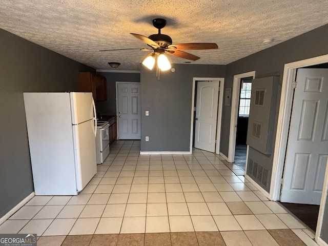 kitchen featuring a textured ceiling, ceiling fan, light tile patterned floors, and white appliances