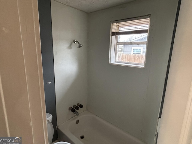 bathroom featuring bathtub / shower combination, a textured ceiling, and toilet